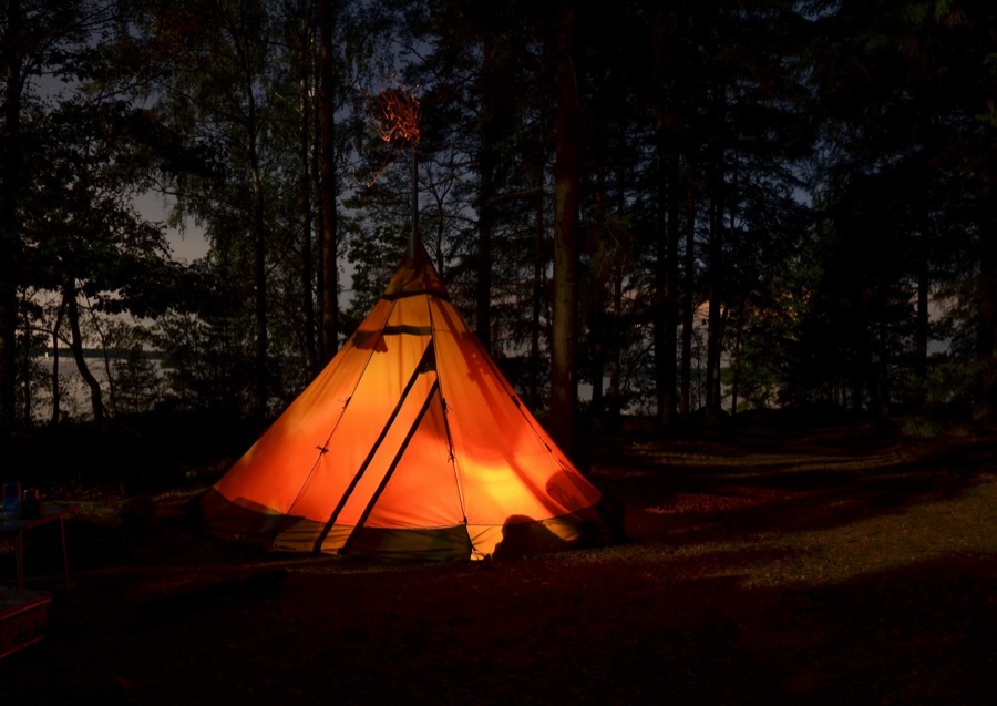 An illuminated tent in a quiet forest at night